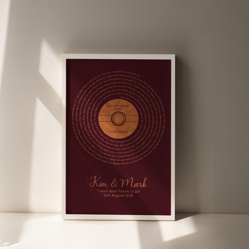 May include: Framed burgundy print featuring a gold-colored vinyl record design with the lyrics to "Can't Help Falling in Love" by Elvis Presley. The print includes the names "Kim & Mark" and the date "10th August 2018".