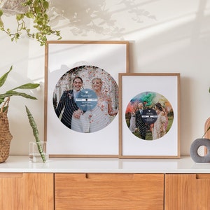 May include: Two framed prints of wedding photos with a record design. The photos are in a circle with the couple in the center. The top print has a blue background and the bottom print has a rainbow background.
