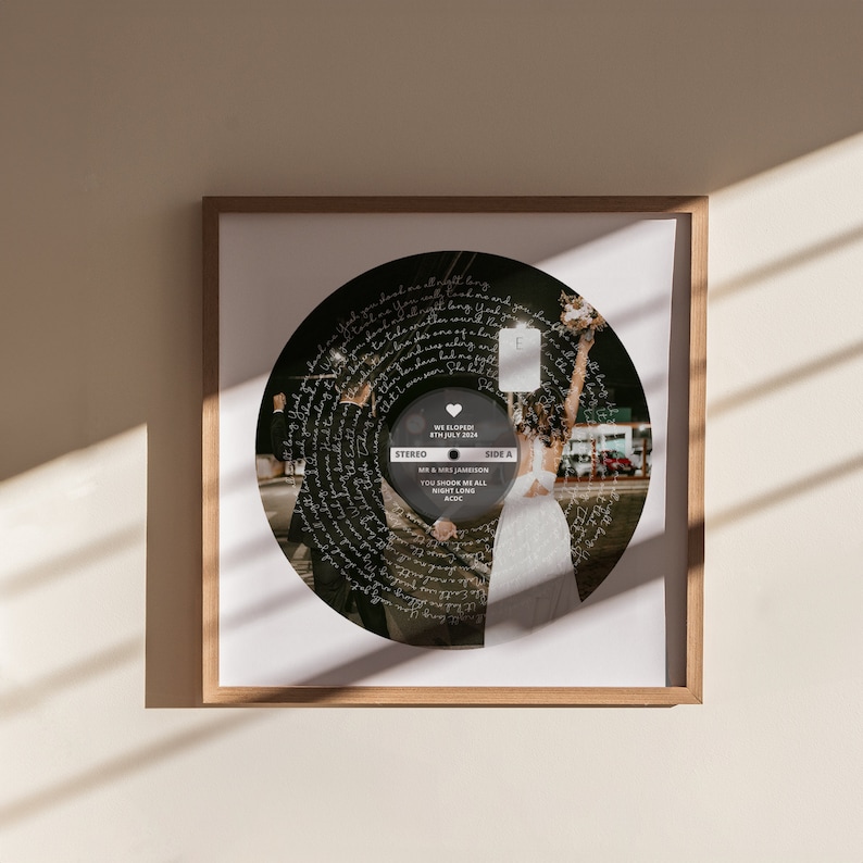 May include: A black and white photo of a couple holding hands and walking away from the camera. The photo is printed on a vinyl record with the words "We Eloped! 8th July 2024" and "MR & MRS JAMIESON YOU SHOOK ME ALL NIGHT LONG ACDC" printed around the edge.