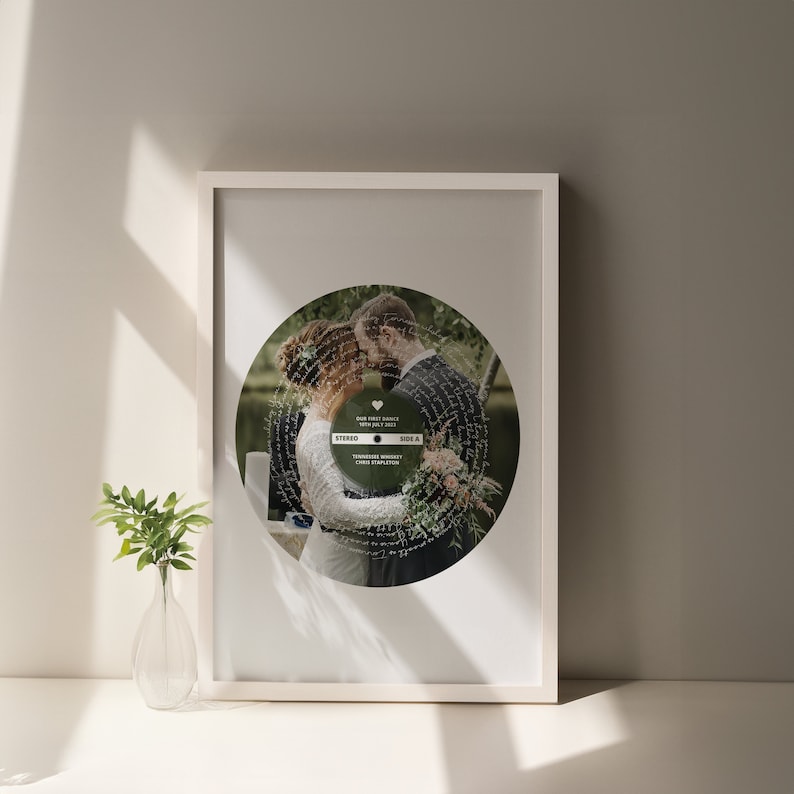 May include: A framed print of a wedding photo with a record-shaped design. The photo shows a couple kissing, and the record design features the words "Our First Dance" and "Tennessee Whiskey" in a vintage style.