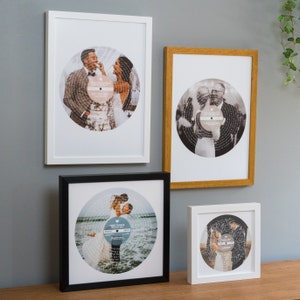 May include: Four framed photos of wedding couples with their first dance song lyrics printed on a record-shaped background. The photos are in white, black, and wood frames.