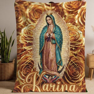 May include: A plush blanket featuring an image of the Virgin Mary with a halo, hands clasped in prayer, and a teal cloak. The background is filled with golden roses and the name "Karina" in a decorative font.