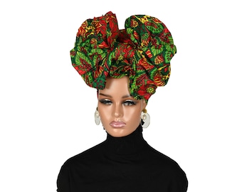 May include: A red and green patterned fabric head wrap tied in a large bow. The wrap is worn on a mannequin with a black turtleneck.