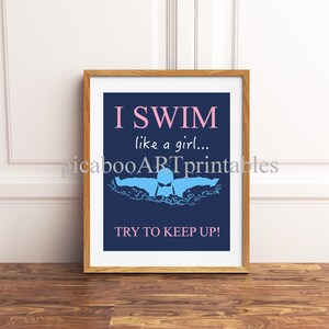 Puede incluir: Una impresión enmarcada con un fondo azul y texto blanco que dice "I SWIM like a girl... TRY TO KEEP UP!" Una silueta azul de un nadador se muestra en el agua.