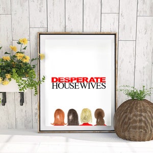 Puede incluir: Una impresión enmarcada con el texto "DESPERATE HOUSEWIVES" en letras rojas. La impresión presenta una ilustración de cuatro mujeres de espaldas al espectador, cada una con un peinado y color de cabello diferente. La impresión está colgada en una pared de madera blanca.