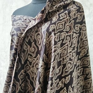 May include: A black and brown patterned fabric with a swirling design. The fabric is draped over a mannequin.