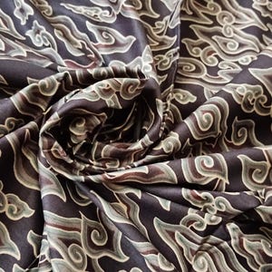 May include: Black fabric with a repeating pattern of stylized clouds in shades of brown, green, and white.