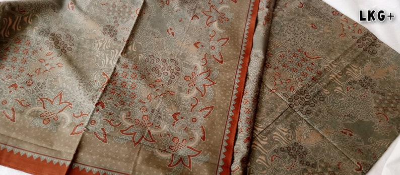May include: A close-up of a fabric with a brown and white floral pattern. The fabric has a red border.