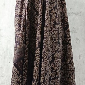 May include: A brown and beige patterned fabric scarf with a repeating cloud design. The scarf is draped over a mannequin.