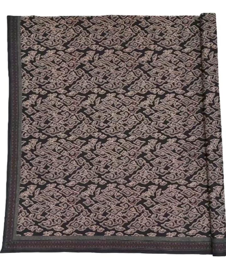 May include: A black fabric with a white and pink patterned design. The fabric is rolled up and has a border around the edges.