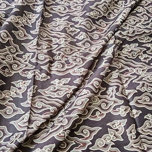 May include: Black fabric with a white cloud pattern. The fabric is folded and has a smooth texture.