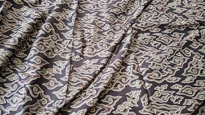May include: Black fabric with a white cloud pattern. The fabric is folded and has a smooth texture.