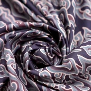 May include: Close-up of a dark blue fabric with a swirling pattern of white and light blue. The fabric has a soft, silky texture.