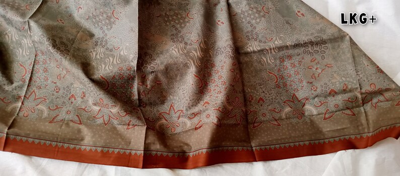 May include: A brown fabric with a white and red floral pattern. The fabric has a brown border with a red trim.