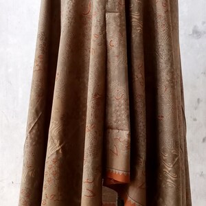 May include: A brown shawl with a floral pattern and orange trim. The shawl is draped over a mannequin.