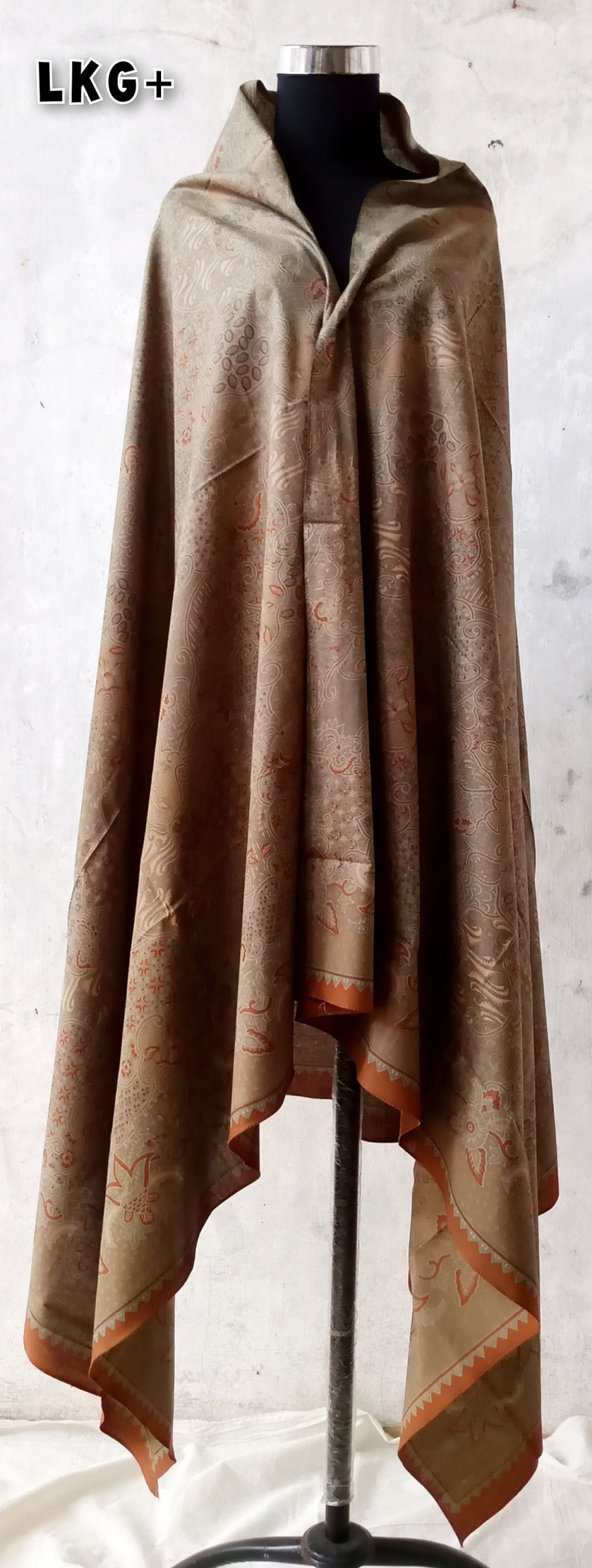 May include: A brown shawl with a floral pattern and orange trim. The shawl is draped over a mannequin.