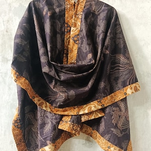 Puede incluir: Un chal de color púrpura oscuro con un patrón detallado de pájaros y follaje. Los bordes y el panel central presentan un borde dorado y marrón contrastante. El texto "LKG+" es visible en la parte superior.