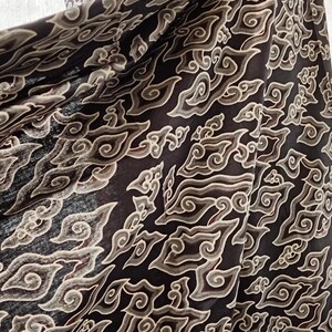 May include: Black fabric with a beige cloud-like pattern. The fabric is draped over a mannequin with the text "LKG+" on the chest.