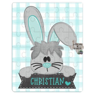 May include: A gray bunny rabbit with blue ears peeks over a black banner with the name "CHRISTIAN" written in teal blue letters and a teal blue heart.