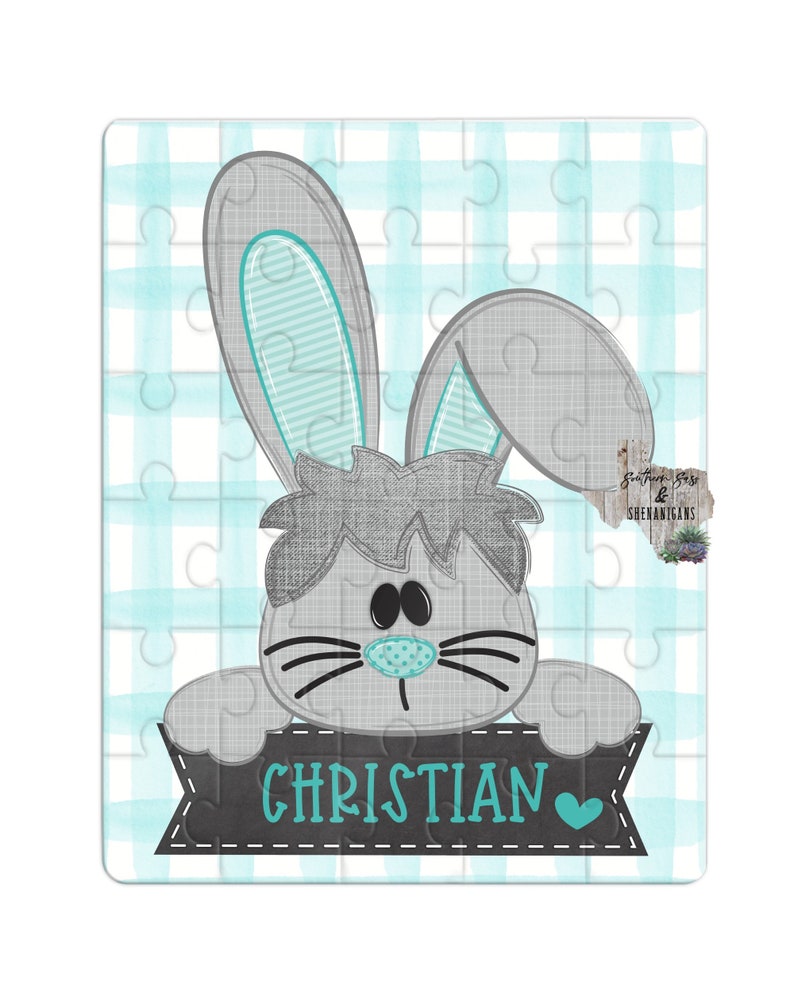 May include: A gray bunny rabbit with blue ears peeks over a black banner with the name "CHRISTIAN" written in teal blue letters and a teal blue heart.
