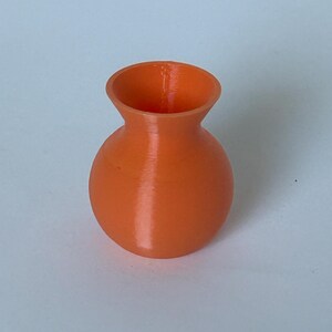 May include: A small, orange ceramic vase with a rounded body and a slightly flared opening.