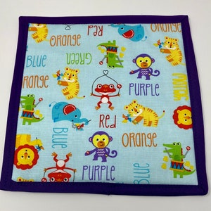 May include: A blue fabric square with a purple border. The fabric has a repeating pattern of animals and the words "orange", "red", "purple", "blue", and "green".