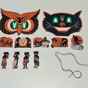 May include: A collection of vintage Halloween decorations featuring an owl, a grinning black cat, and various other festive cutouts. The decorations are in orange, black, and white, with a string for hanging. The collection includes images of cats, pumpkins, and a witch.