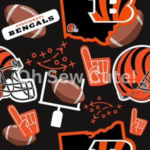 Könnte beinhalten: Schwarzer und orangefarbener Stoff mit einem sich wiederholenden Muster aus Bildern der Cincinnati Bengals. Das Muster enthält Footballhelme, Fußbälle, das Teamlogo und die Worte "Cincinnati Bengals".
