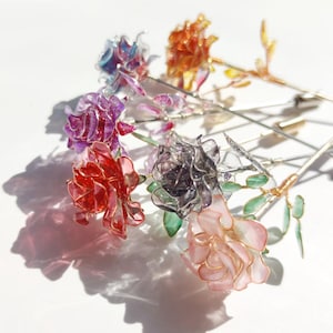 May include: A set of six colorful resin rose pins. Each pin features a different color rose with a metallic wire stem and leaves. The roses are translucent and have a sparkly finish.