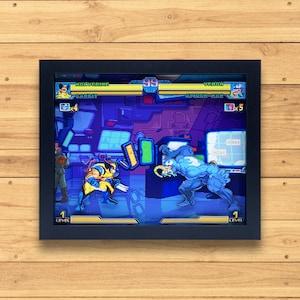 Puede incluir: Una impresión enmarcada de pixel art de una escena de videojuego con Wolverine y Venom luchando. Los personajes están en un fondo azul y morado con el texto "Wolverine" y "Venom" encima de ellos. El texto "Round 1" está en la parte superior central de la imagen.