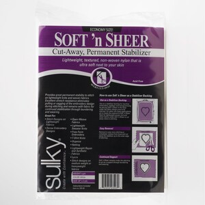 以下が含まれることがあります： Sulky Soft 'n Sheerのカットアウェイ永久安定剤のパッケージ。パッケージは白と紫で、「エコノミーサイズ！」と「軽量、テクスチャード加工、不織布ナイロン」と書かれています。刺繍用です。
