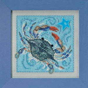 May include: A framed needlepoint featuring a blue crab with orange claws and a blue star on a light blue background. The crab is the focal point, set against a textured, wave-like pattern. The frame is a solid light blue.