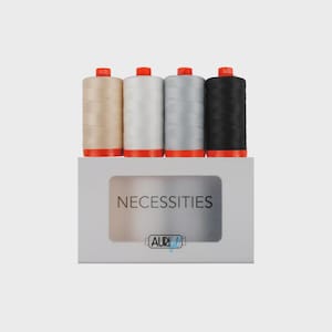 Puede incluir: Un juego de cuatro carretes de hilo en beige, blanco, gris claro y negro, cada uno con una tapa de color naranja brillante. Los carretes se presentan en una caja rectangular blanca con ventana transparente, con el texto NECESSITIES y el logo de Aurifil.
