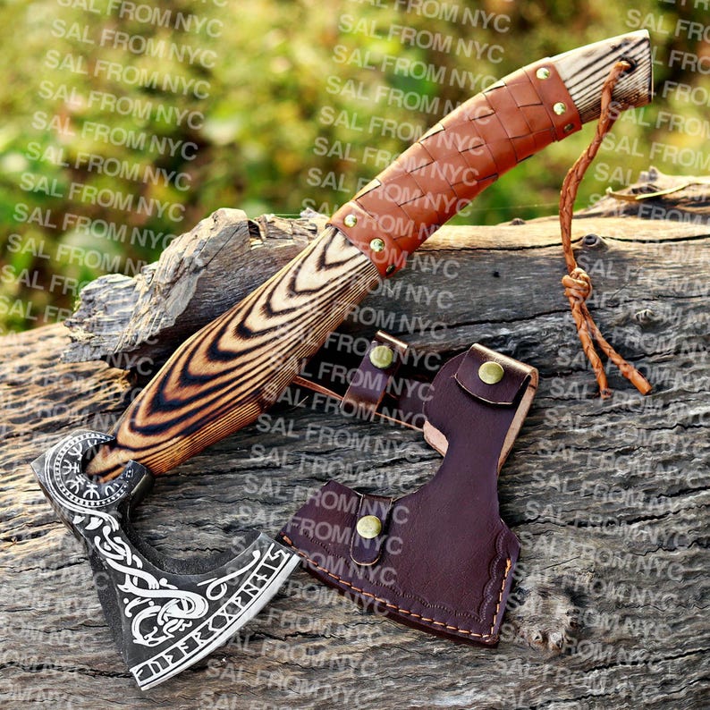 May include: A handcrafted axe and knife set with wooden handles and leather accents. The axe head features intricate engraved designs. The set includes a leather sheath for the axe. The knife has a brown leather-wrapped handle.