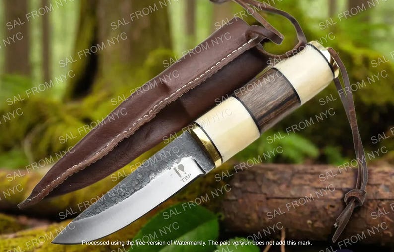 May include: A handcrafted knife with a wooden and bone handle, a silver blade, and a brown leather sheath. The knife has a rustic, outdoorsy aesthetic, suitable for camping or hunting. The blade has the text "TBP".