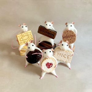 May include: A charming image of six white mice, each holding a different biscuit. The biscuits include a Custard Cream, a Bourbon, a Digestive, and a jam-filled shortbread. The mice are standing on a light-colored surface.