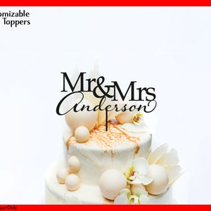 May include: A black and white cake topper with the text "Mr & Mrs Anderson" on a white cake with white and gold decorations.