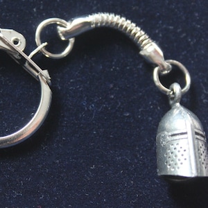 May include: Silver key chain with a knight's helmet charm. The helmet is detailed with a mesh design and a cross on the front.