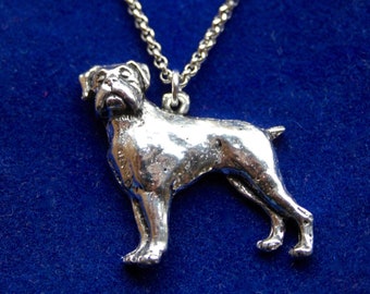 Puede incluir: Collar con colgante de perro Boxer plateado. El colgante representa un perro Boxer detallado en posición de pie. La cadena del collar es plateada, sobre un fondo azul oscuro.