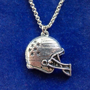 May include: A silver necklace with a football helmet pendant featuring an American flag design.