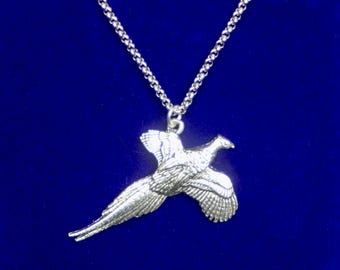 May include: A silver-toned metal pendant shaped like a pheasant in flight, suspended from a matching silver-toned link chain. The bird figure features detailed wing and tail feather textures, with the head turned to the right, creating a dynamic silhouette.