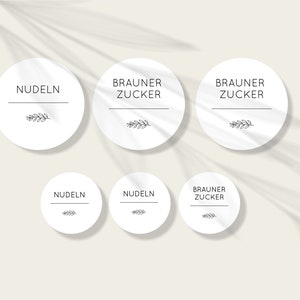 Può includere: Sei etichette rotonde bianche con testo nero e un piccolo disegno di ramoscello. Le etichette riportano "BRAUNER ZUCKER" e "NUDELN".