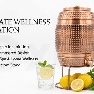 May include: A copper water dispenser with a hammered texture, a lid, and a spigot, resting on a metal stand. The text ULTIMATE WELLNESS HYDRATION, Natural Copper Ion Infusion, Artisanal Hammered Design, Perfect for Spa & Home Wellness, Includes Custom Stand is visible.