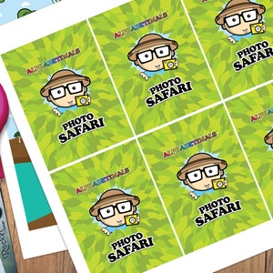 May include: Six printable cards with a green leafy background and a cartoon character wearing a safari hat and glasses holding a camera. The text on the cards reads "Alphabetimals Photo Safari".
