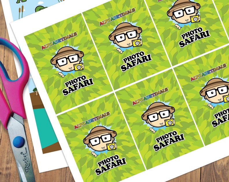 May include: Six printable cards with a green leafy background and a cartoon character wearing a safari hat and glasses holding a camera. The text on the cards reads "Alphabetimals Photo Safari".