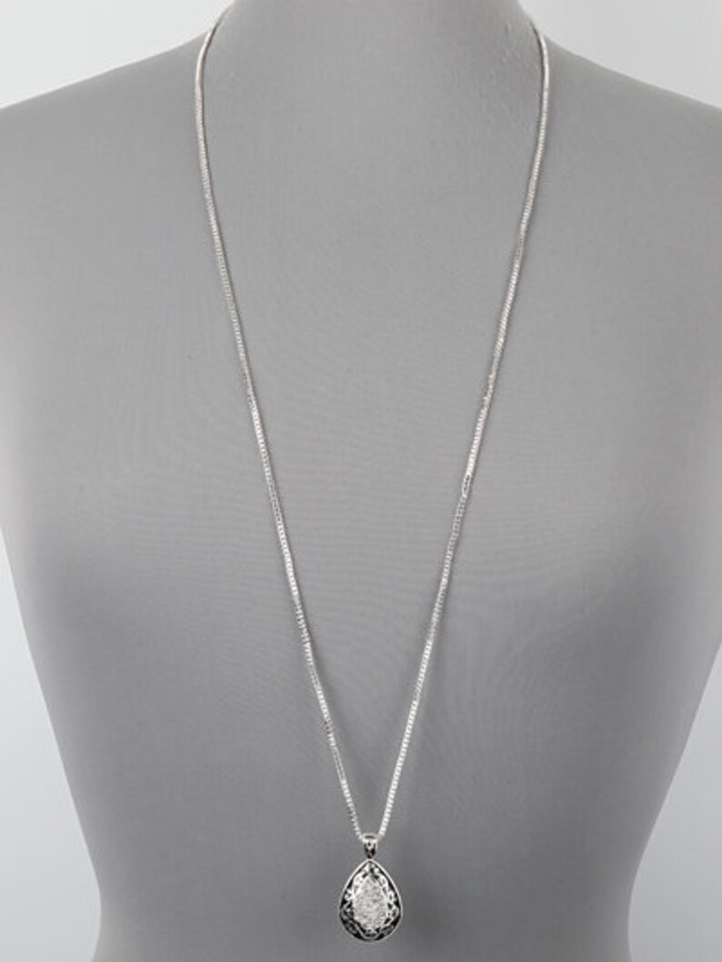 Puede incluir: Un collar de cadena de plata con un colgante en forma de l&aacute;grima. El colgante est&aacute; decorado con un dise&ntilde;o texturizado.