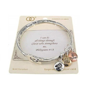May include: Silver bangle bracelet with charms, including a musical note, a cross, and a guitar. The bracelet has an inscription that reads "I can do all things through Christ who strengthens me. Philippians 4:13".