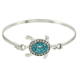 May include: A silver bangle bracelet with a turquoise crystal-encrusted turtle charm.