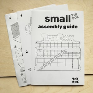 May include: Black and white assembly guide for a small toy box. The guide shows the steps to assemble the toy box, which has a slide and multiple shelves. The guide is titled "small assembly guide" and features the logo "Toy Box".