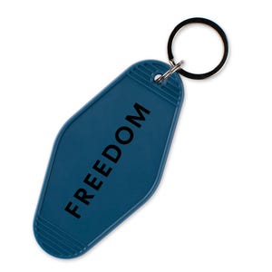 May include: A teal blue motel-style keychain with the word "FREEDOM" printed in black. The keychain has a rectangular shape with rounded edges and a metal key ring attached at the top.